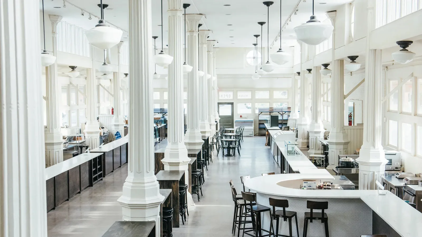 Inside St. Roch Market: white cast iron columns, pendant lights, and vendor counters