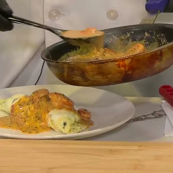 Chef Charles Wilford Sr. spooning shrimp and crawfish sauce over a plated omelet on the FOX 8 Morning Show