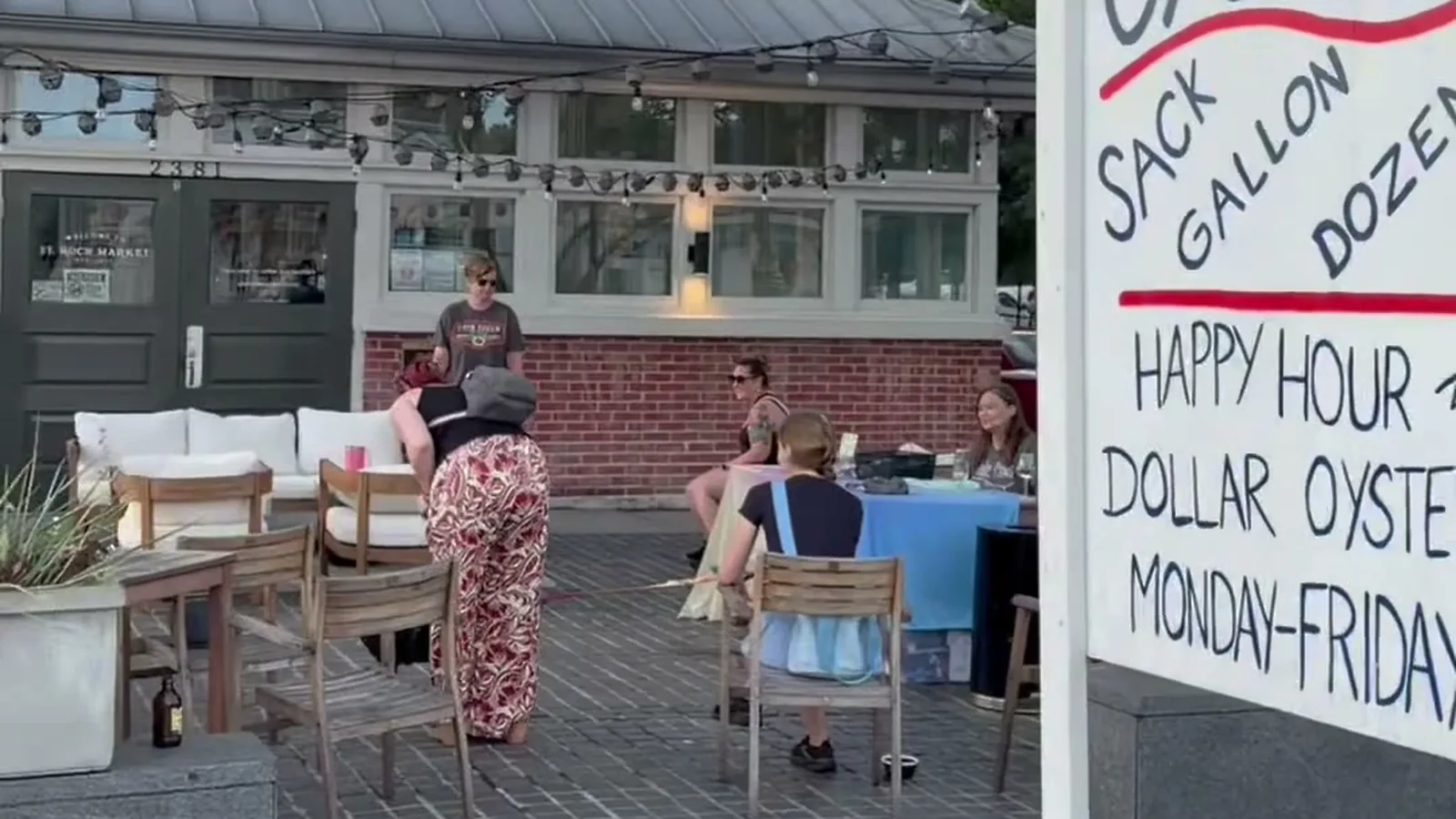 The St. Roch Market patio during a dog adoption event, with guests at tables under string lights and the Salted Pearl oysters sign in the foreground