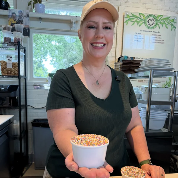 Alison Grice Barrios of Olive & Co holding a rainbow sprinkle dot cake at St. Roch Market