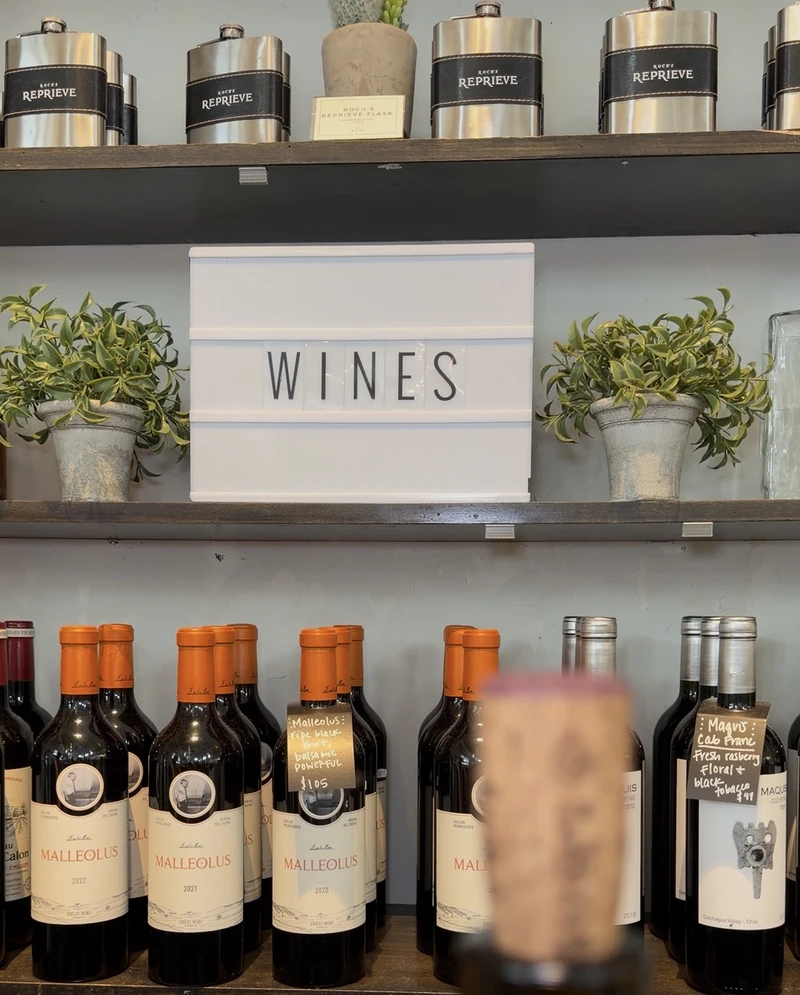 The wine shelf at Roch's Reprieve with the illuminated WINES sign above bottles of Emilio Moro Malleolus